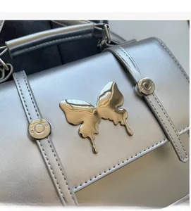 Detail of silver faux leather texture and metallic butterfly ornament on a stylish handbag