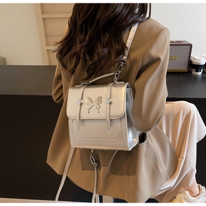 Detail of silver metallic backpack with butterfly ornament and dual-strap design