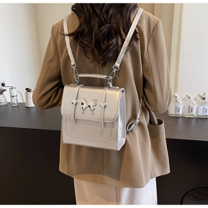Silver metallic mini backpack with butterfly hardware shown worn on a model's back