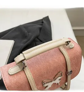 Detail of pink matte suede handbag featuring a decorative metal butterfly clasp and handle