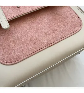 Detail of pink suede and beige faux leather stitching with protective metal studs