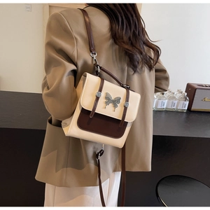 Detail of vintage beige and brown patchwork bag with metal butterfly clasp on shoulder