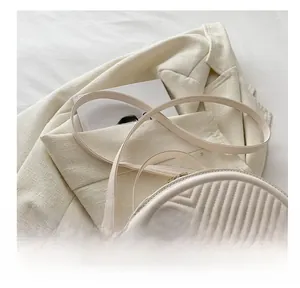Detail of cream quilted semi-circular bag with V-shaped stitching and slim shoulder strap