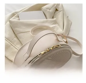 Detail of V-shaped quilted texture on off-white PU leather half-moon handbag