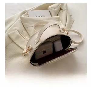 Detail showing the internal storage capacity of the beige half-moon faux leather saddle bag