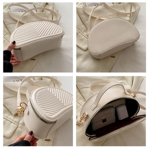 Detail view of cream shell bag with V-shaped quilting, gold hardware and interior capacity
