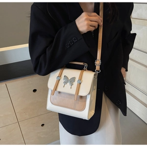 Model wearing a retro cream and brown crossbody bag with silver butterfly buckle detail