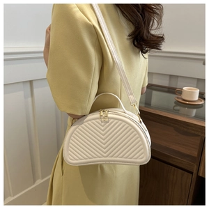 Model wearing a cream crescent bag with V-shaped quilting and gold metal zippers