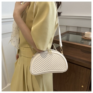 Close-up of white half-moon shoulder bag featuring V-quilted faux leather and gold hardware