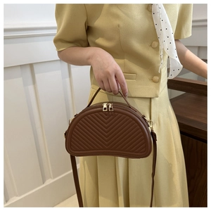 Detailed view of brown quilted saddle bag with dual gold zippers and adjustable strap