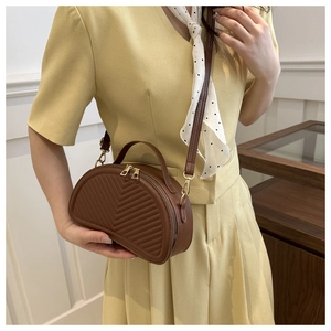 Detail of V-quilted dark brown half-moon bag with gold zippers and detachable strap