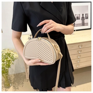 Detail of beige crescent handbag featuring V-quilted texture and elegant top handle