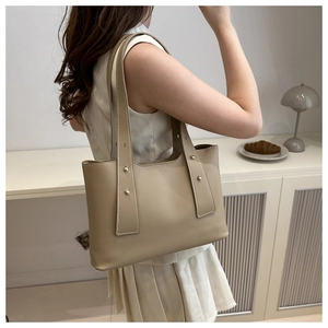Detail view of khaki leather tote bag with metallic stud accents on the side