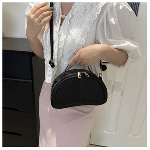 Detail of black semi-circular saddle bag with V-shaped quilting and gold metal zippers