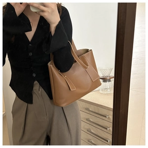 Mirror selfie showing the medium size of a brown leather tote bag with contrast stitching
