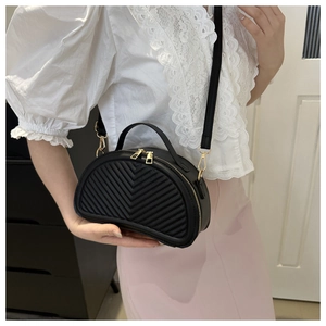 Detail of black semi-circular crossbody bag featuring V-quilted faux leather and gold hardware