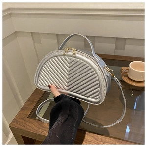 Detailed close-up of V-quilted silver semi-circle handbag with golden hardware