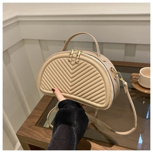 Detailed close-up of beige crescent bag featuring elegant V-shaped quilted texture