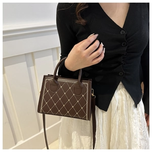 Sac à main matelassé marron foncé avec broderie cœur, porté avec un cardigan noir