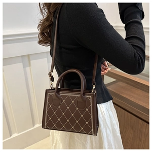 Détail d'un sac à main vintage en cuir marron avec motif losange brodé et boucles dorées