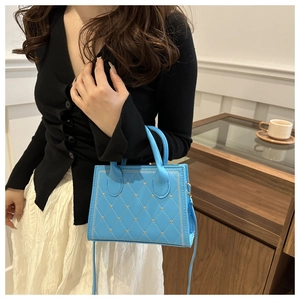 Sac bandoulière bleu matelassé porté avec une tenue chic dans un café moderne