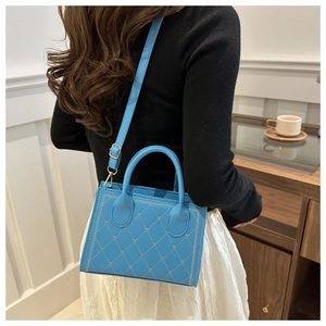 Sac à main bleu matelassé avec surpiqûres en cœur porté par un mannequin dans un salon