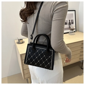 Gros plan détaillé du sac matelassé noir avec coutures blanches et finitions dorées