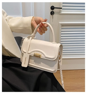 Detail of elegant cream leather square handbag with golden twist lock and fashion tag