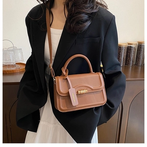 Close-up of brown leather handbag with gold twist lock and a fashion brand hangtag