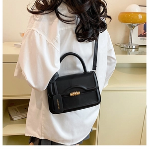 Classic black faux leather flap handbag with gold cylindrical clasp and shoulder strap