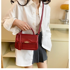 Detail view of a vintage dark red leather crossbody bag with a gold metal lock and tag
