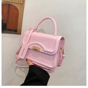 Close-up of pink faux leather crossbody bag with golden metal buckle and brand tag