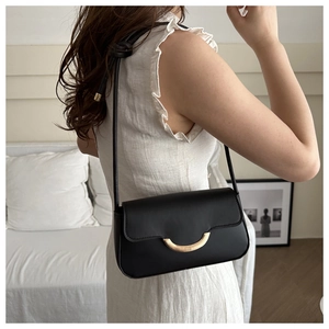 Détail du sac à bandoulière en cuir noir mat avec une boucle dorée élégante en demi-lune