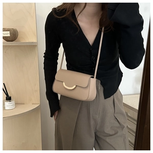 Détail d'un sac bandoulière en cuir marron avec fermoir doré porté par un mannequin