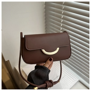 Détail d'un sac bandoulière marron foncé avec fermoir doré et fine bandoulière