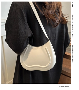 Detail of white leather hobo bag featuring a unique U-shaped design and slim shoulder strap