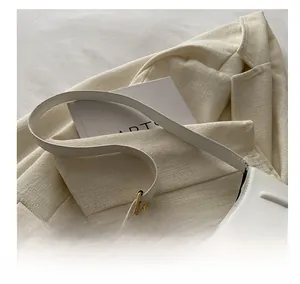 Detail of white leather shoulder bag with wide strap and golden circular metal buckle
