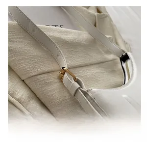 Detail of adjustable gold metal buckle and premium white leather strap on shoulder bag