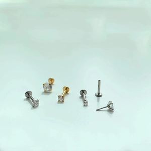 Flat lay of minimalist gold and silver prong-set crystal labret studs in various sizes