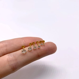 Detailed view of six gradient sizes of gold labret piercings with white cubic zirconia