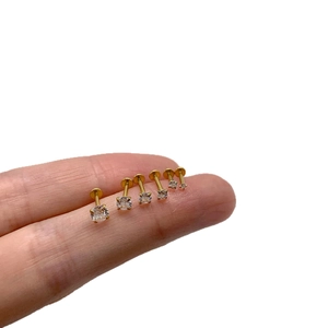 Set of six gold labret studs with cubic zirconia gems in various sizes on a finger
