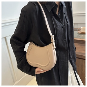 Close-up of beige crescent shoulder bag with embossed detailing on premium PU leather