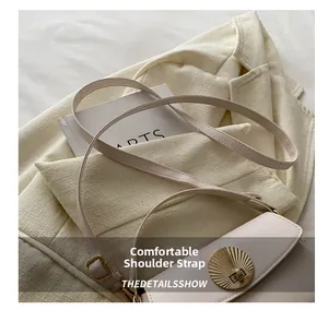 Detail view of cream shoulder bag with golden fan-shaped buckle on beige blazer