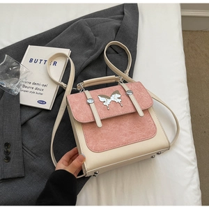 Detail of pink and beige suede patchwork bag with silver butterfly charm and top handle