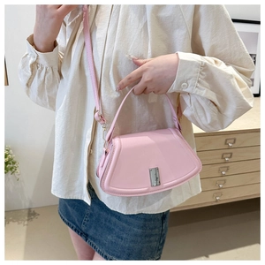 Lifestyle shot of light pink crossbody shell bag with silver buckle and adjustable strap