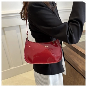 Glossy patent leather burgundy underarm bag with gold zipper and minimalist crescent shape