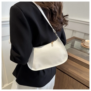 Fashionable white glossy crescent shoulder bag with golden hardware shown on a model