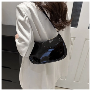 Minimalist black patent leather shoulder bag with sleek crescent shape and golden zipper