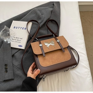 Detailed shot of brown vintage handbag with butterfly buckle on white bedding