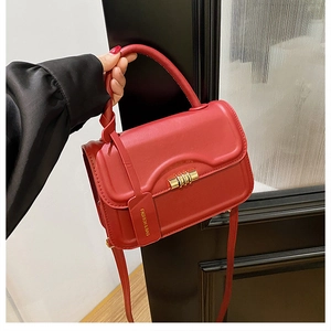 Elegant red leather shoulder bag with gold twist lock and wavy flap on a minimalist background